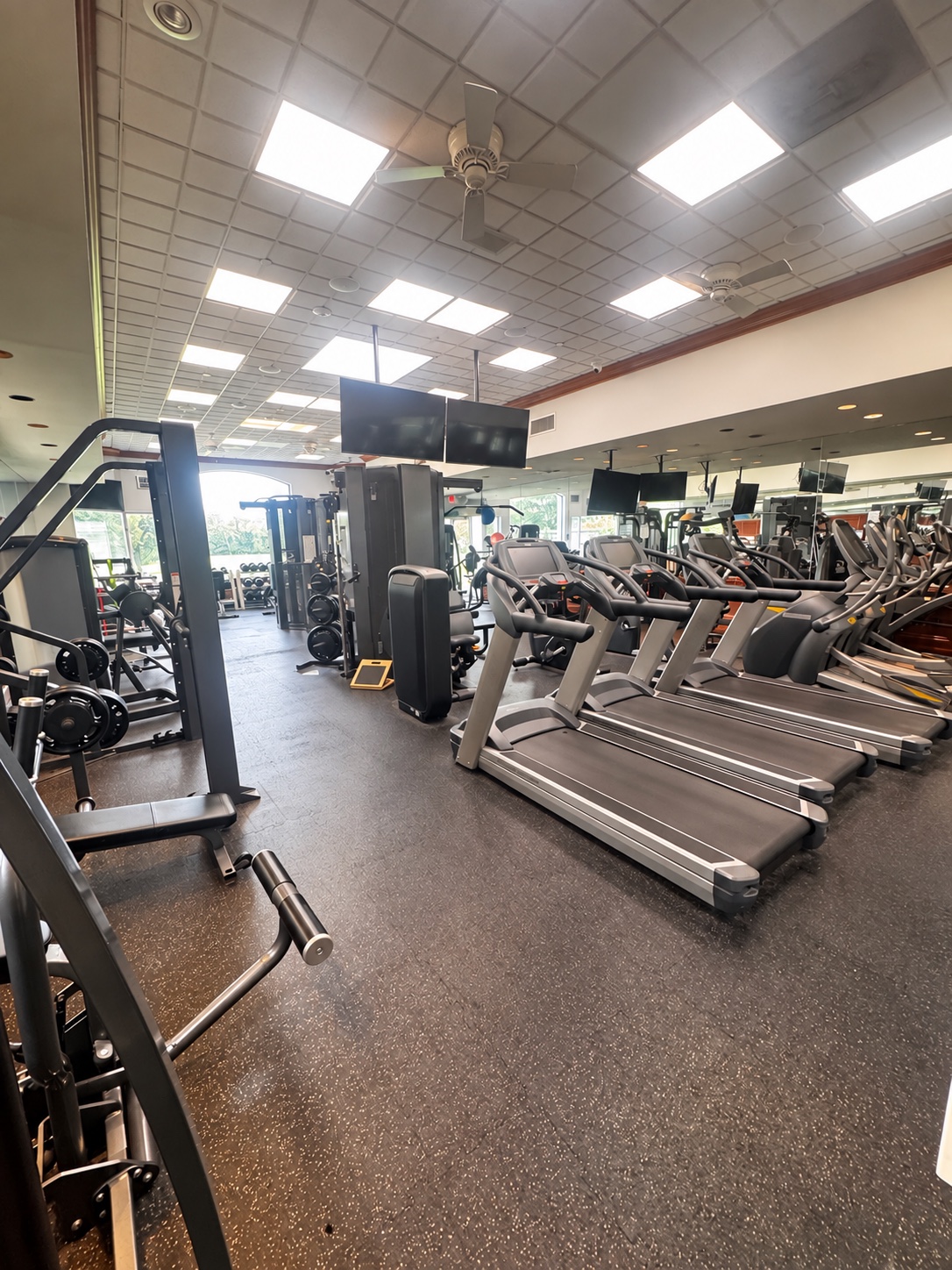 Crowded gym interior with treadmills and strength machines arranged closely, leaving limited open floor for movement.